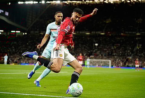 Manchester United's Noussair Mazraoui clears the ball in front of Brentford's Kevin Schade during the Premier League soccer match between Manchester United and Brentford in Manchester, England.