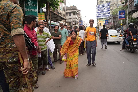 A security personnel keeps vigil as people wait in queues before casting their votes in the second and final phase of the West Bengal Assembly elections, at a polling station in Kolkata.