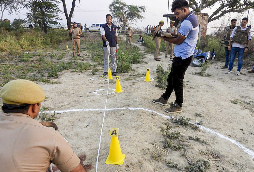 | Photo: PTI : Police and other other officials present at the site as they investigate the triple murder case, in Bulandshahr, Uttar Pradesh.