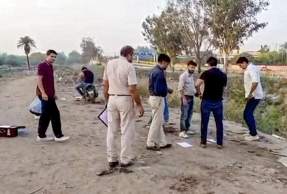 Police and other other officials present at the site after an alleged accused wanted in a murder case was apprehended following an encounter at Ashok Vihar area, in New Delhi.