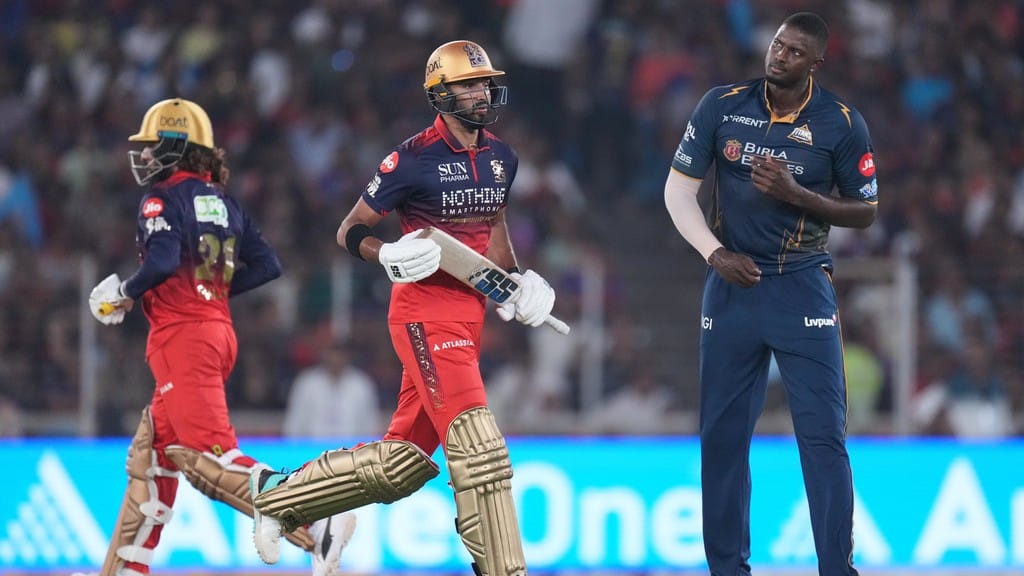 Devdutt Padikkal and Rajat Patidar run between the wickets as Jason Holder looks on during the Indian Premier League match between Gujarat Titans and Royal Challengers Bengaluru in Ahmedabad. - Photo: AP