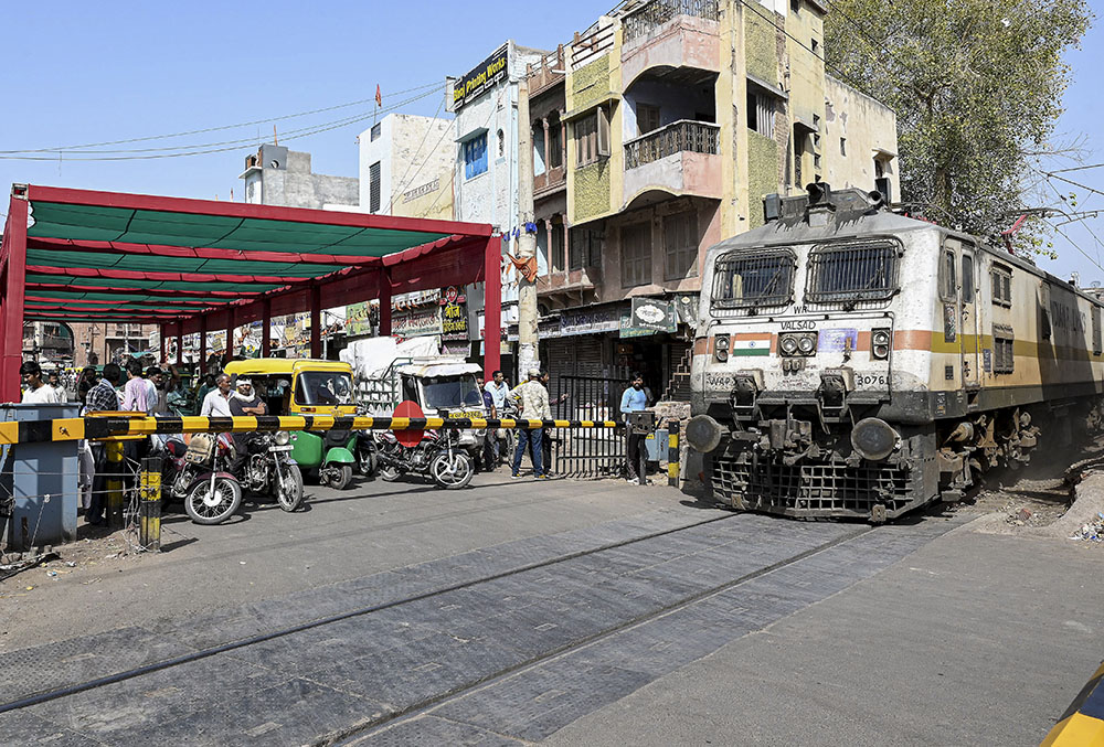 Commuters wait under a temporary shade arranged by local authorities to shield them from scorching heat near a railway crossing.