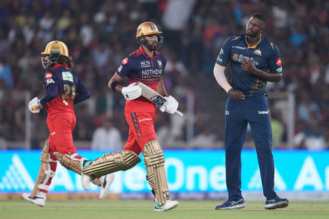 Royal Challengers Bengaluru's Devdutt Padikkal and Royal Challengers Bengaluru's captain Rajat Patidar run between the wickets as Gujarat Titans' Jason Holder looks on during the Indian Premier League cricket match between Gujarat Titans and Royal Challengers Bengaluru in Ahmedabad, India.
