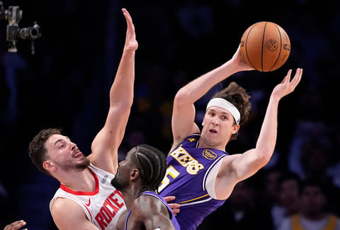 Los Angeles Lakers guard Austin Reaves, right, passes while under pressure from Houston Rockets center Alperen Sengun, left, while center Deandre Ayton stands by during the second half in Game 5 of a first-round NBA playoffs basketball series in Los Angeles.