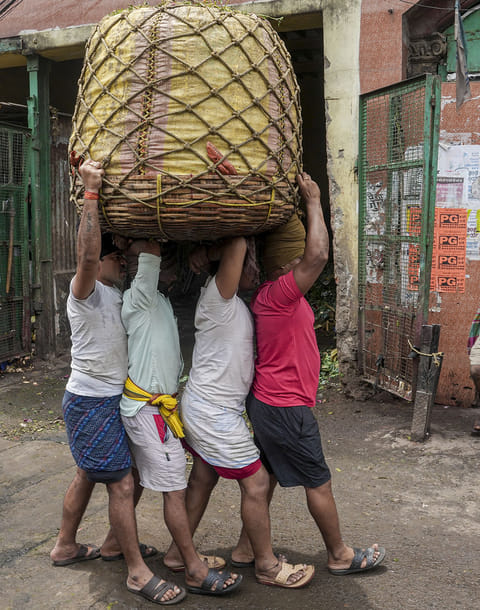 Workers carry a basket of vegetables at a wholesale vegetable market on International Labour Day, in Kolkata, West Bengal.