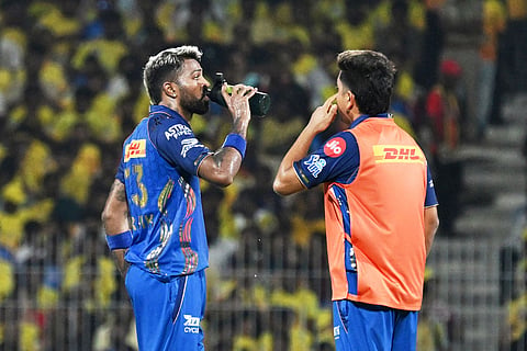 Mumbai Indians' captain Hardik Pandya, left, gets a drink during the Indian Premier League cricket match between Chennai Super Kings and Mumbai Indians in Chennai, India.