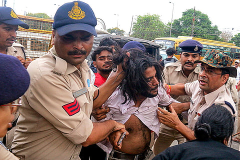 Police personnel detain a man as he protests during a demolition drive carried out in Bhopal, Madhya Pradesh.