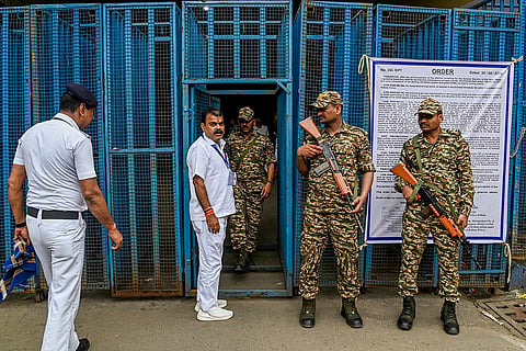 Security personnel stand guard as BJP candidate from Jorasanko constituency, Vijay Ojha arrives outside a strong room, ahead of the counting of votes for the West Bengal Assembly elections, at the Khudiram Anushilan Kendra, in Kolkata.