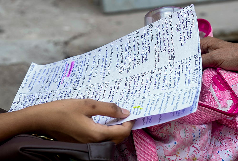 An aspirant revises from notes before appearing for the National Eligibility-cum-Entrance Test (NEET) UG-2026 examination, at Narela area, in New Delhi.
 - | Photo: PTI/Shahbaz Khan
