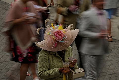 A woman holds drinks as people pass before the 152nd running of the Kentucky Derby horse race at Churchill Downs in Louisville, Kentucky.