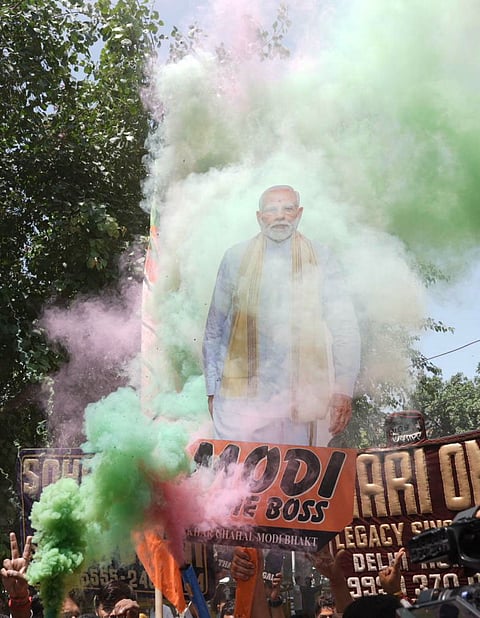 BJP supporters with cutouts and slogans celebrate in Delhi.