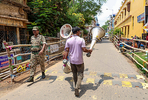 A worker carries public announcement speakers on the eve of counting and results of the West Bengal Assembly polls, in Birbhum, West Bengal.