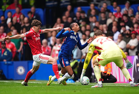 Chelsea's Joao Pedro, center, falls to the ground after pressure from Nottingham Forest's Ryan Yates during the English Premier League soccer match between Chelsea and Nottingham Forest in London.