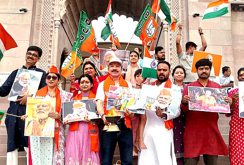 People hold placards of Prime Minister Modi and raise party flags to celebrate party’s win across West Bengal and Assam Assembly elections, in Varanasi, Uttar Pradesh.