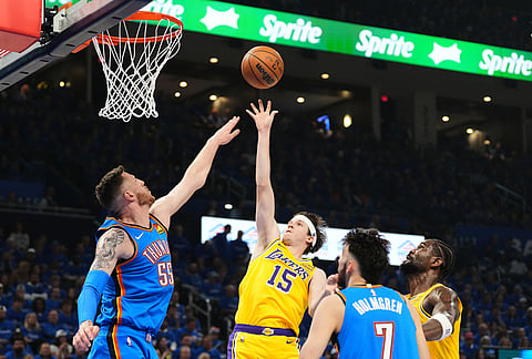 Los Angeles Lakers guard Austin Reaves (15) shoots over Oklahoma City Thunder's Isaiah Hartenstein (55) as Chet Holmgren (7) looks on in the first half of Game 1 in a second-round NBA basketball playoffs series in Oklahoma City.
