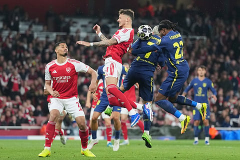 Arsenal's Ben White jumps for the ball with Atletico Madrid's Antoine Griezmann and Ademola Lookman, right, during a Champions League semifinal, second leg, soccer match between Arsenal FC and Atletico Madrid in London.