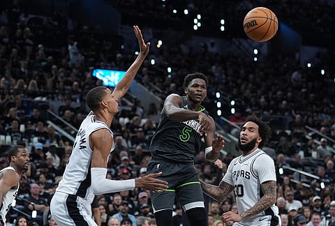 Minnesota Timberwolves guard Anthony Edwards (5) pass around San Antonio Spurs forward Victor Wembanyama (1) and forward Julian Champagnie (30) during the first half in Game 2 of a second-round NBA playoffs basketball series in San Antonio.