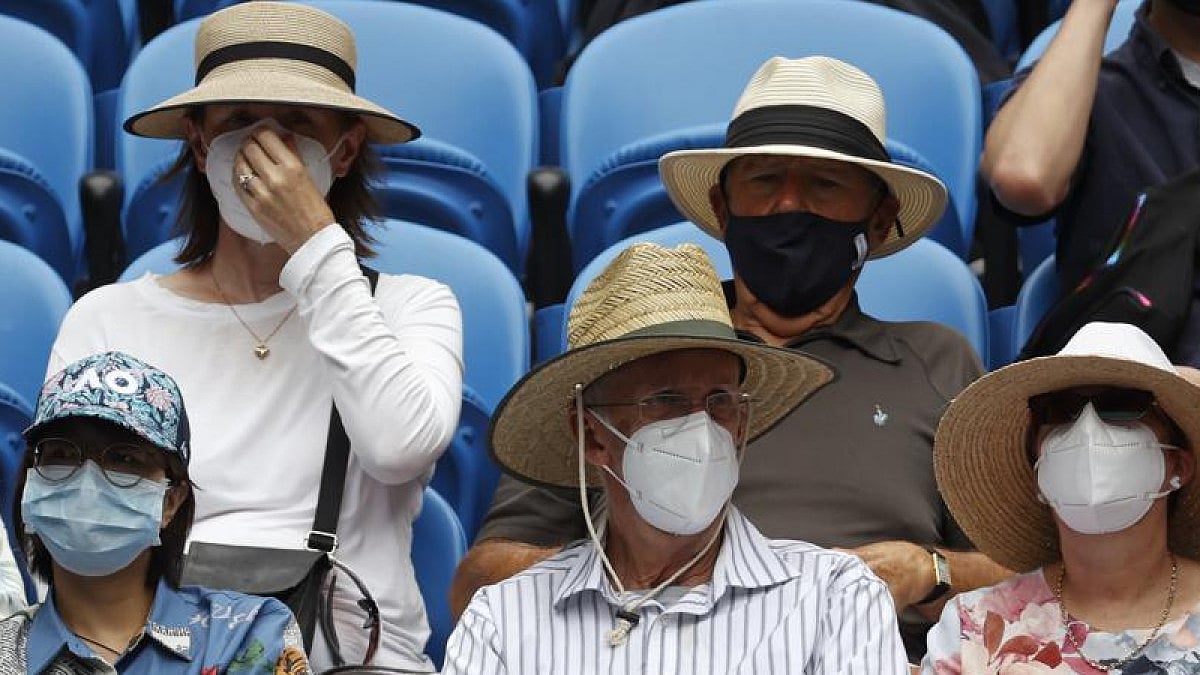 Masked spectators watch Australian Open tennis championship.
