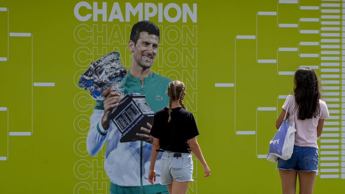 Fans look at a photo of defending Australian Open champion Novak Djokovic.