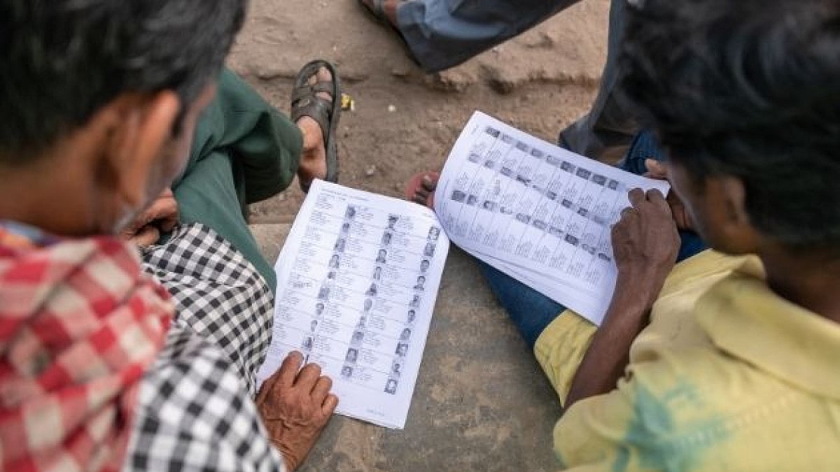 Voters check voter rolls before casting their ballots at a polling station