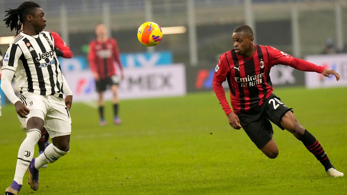 Juventus' Moise Kean (L) and AC Milan's Pierre Kalulu eye the ball in Serie A 2021-22.