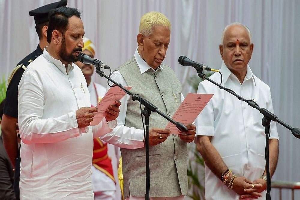 Karnataka Governor Vajubhai Vala (C) administering the oath of office to Laxman Savadi (L) during the swearing-in ceremony of Karnataka BJP Government, at Raj Bhavan in Bengaluru in 2019