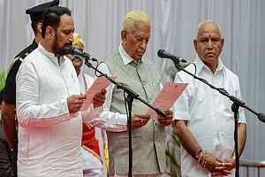 Karnataka Governor Vajubhai Vala (C) administering the oath of office to Laxman Savadi (L) during the swearing-in ceremony of Karnataka BJP Government, at Raj Bhavan in Bengaluru in 2019
