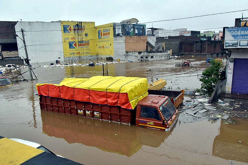 Vehicles lie partially submerged in floodwater following heavy rains, at Falaknuma, in Hyderabad.