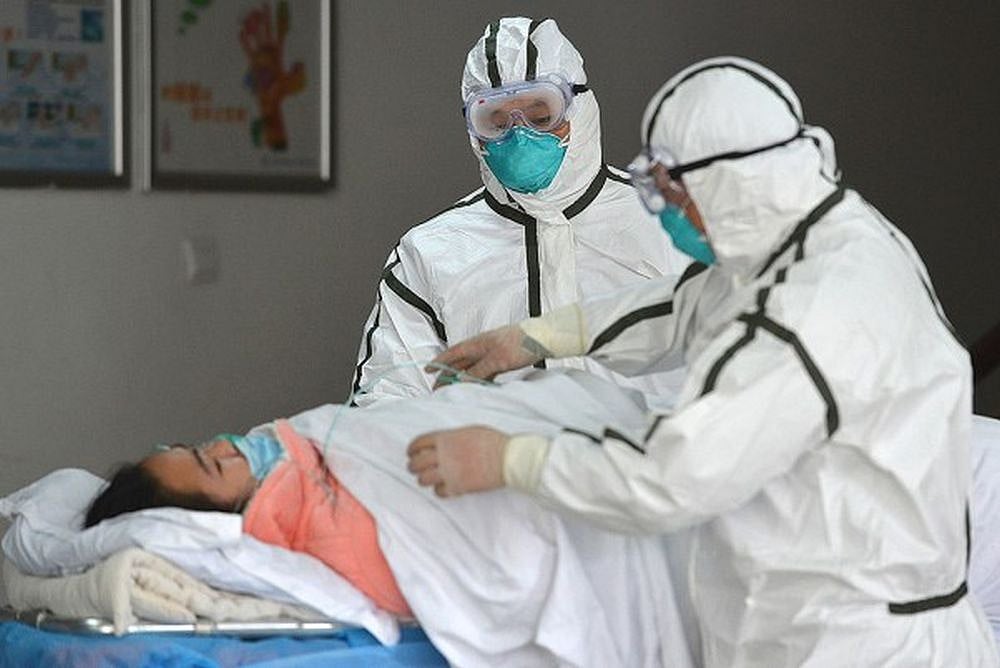 Medical workers in protective suits move a coronavirus patient into an isolation ward at a hospital in central China