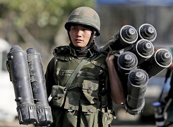 An Indian Army soldier carries used ammunition boxes outside the government building where suspected militants had taken refuge during a gun battle.
