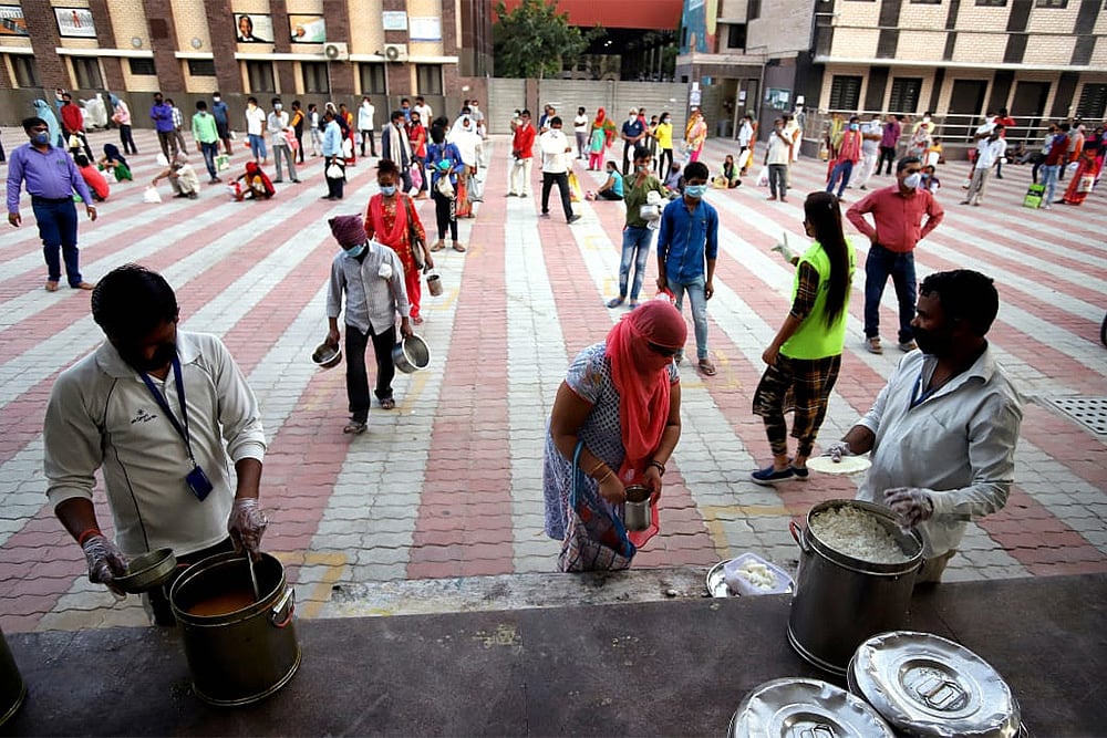 Migrant workers, sheltered inside a Delhi Government school, being provided food items during the nationwide complete lockdown imposed to contain the coronavirus pandemic in east Delhi. (PTI)