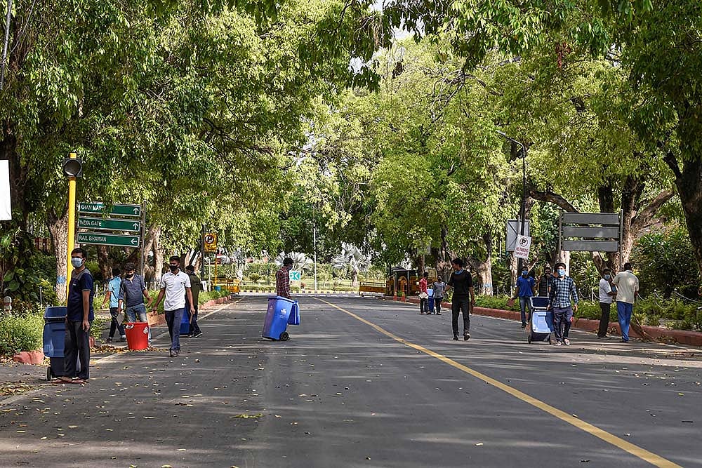 Workers are seen cleaning a road near Vayu Bhawan, during a nationwide lockdown in the wake of coronavirus pandemic, in New Delhi.