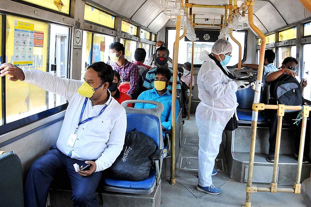 A state government bus conductor wearing a protective suit issue tickets to passengers in a bus after authorities eased restrictions, during the ongoing COVID 19 nationwide lockdown, at Garia terminus in Kolkata.