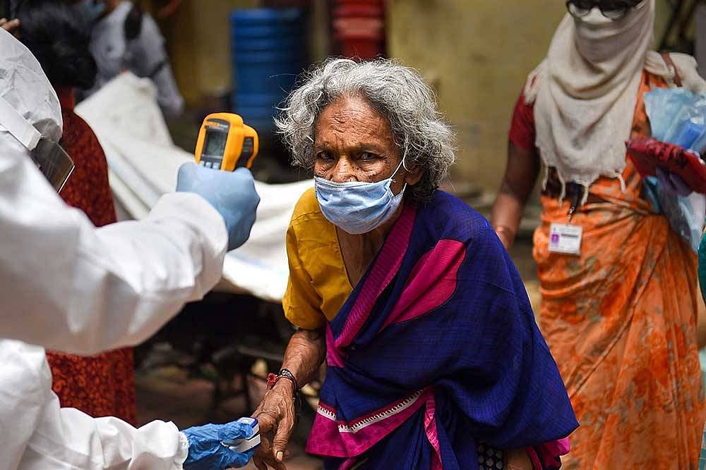 A health worker scans temperature of an elderly woman while conducting door-to-door medical check-up of the residents of Dharavi slum, amid COVID pandemic in Mumbai.
