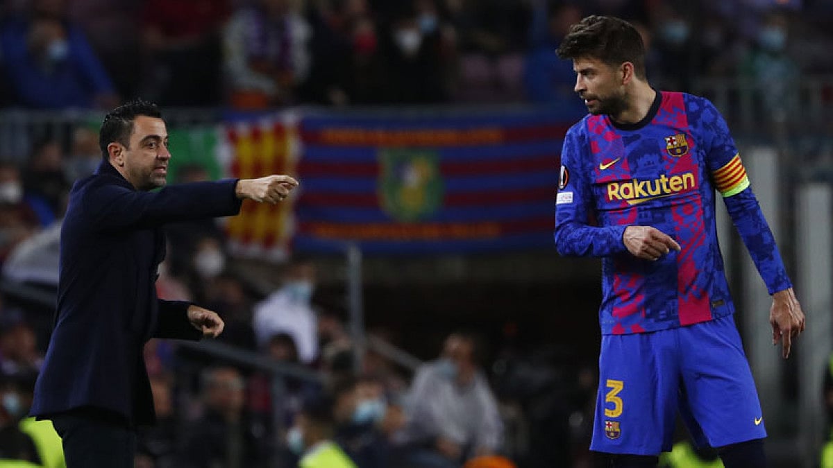 Barca coach Xavi Hernandez talks to Gerard Pique during their Europa League match against Napoli.