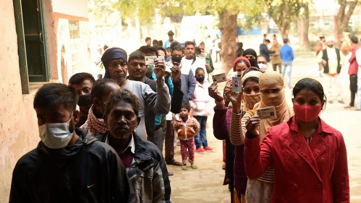 People wait in queues at a polling station to cast their votes for the fourth phase of UP polls.