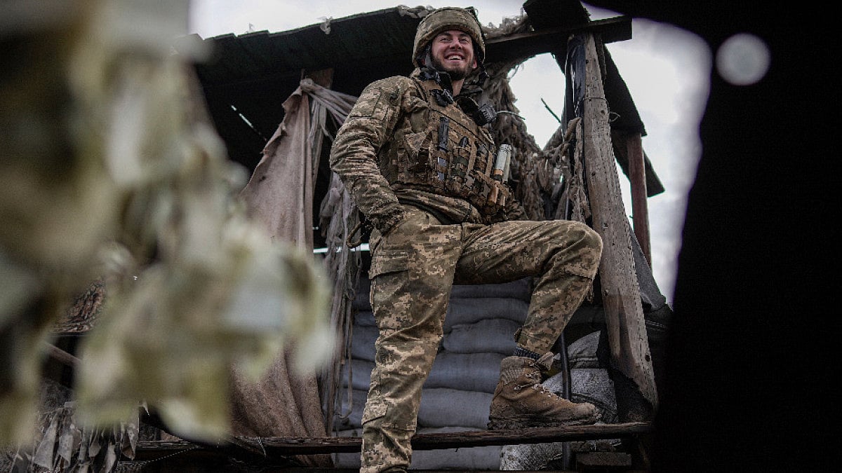 A Ukrainian serviceman smiles standing at his position at the line of separation between Ukraine-hel