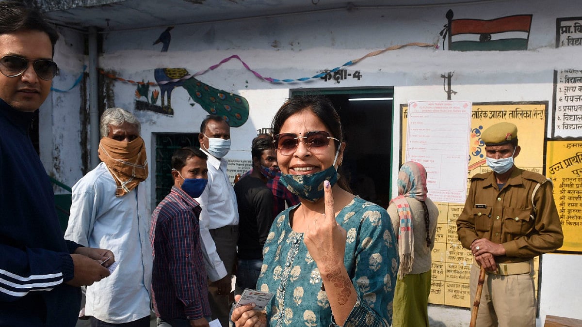 Security personnel stand guard as a citizen shows her finger marked with indelible ink