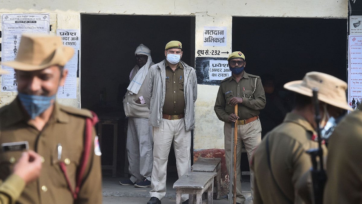 Security personnel stand in a queue as citizens cast their vote for the fifth phase of UP election