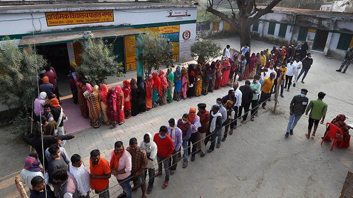 People stand in queue to cast their votes during the 5th phase of Uttar Pradesh state legislature 