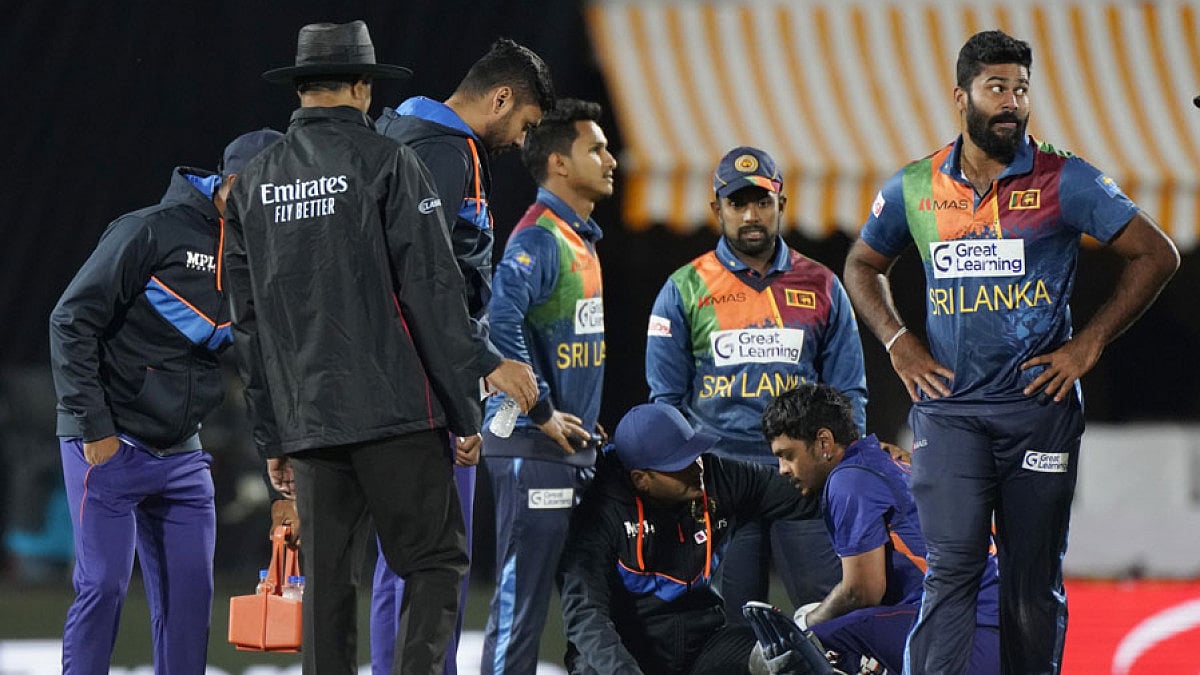 Indian team doctor checks Ishan Kishan, sitting center right, after a ball hits on his helmet.