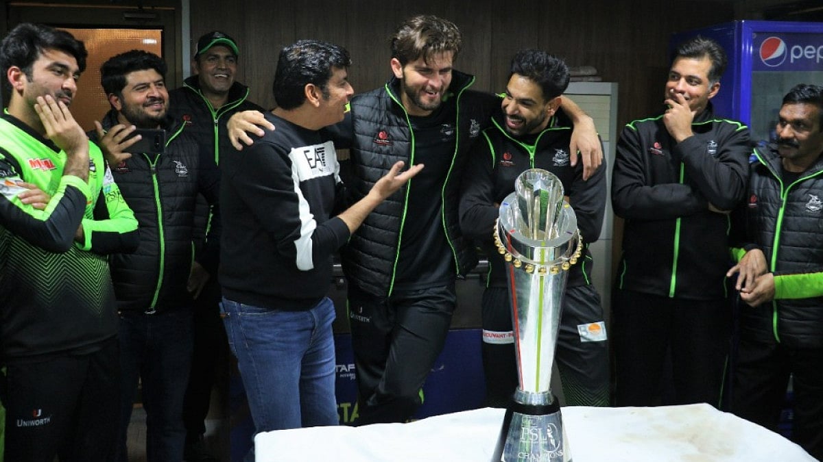 Lahore Qalandars captain Shaheen Shah Afridi (C) looks at the PSL 2022 winners' trophy on Sunday.  