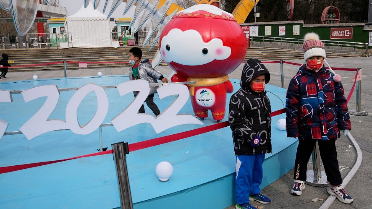Children stand near  the 2022 Winter Paralympics mascot Shuey Rhon Rhon in Beijing.