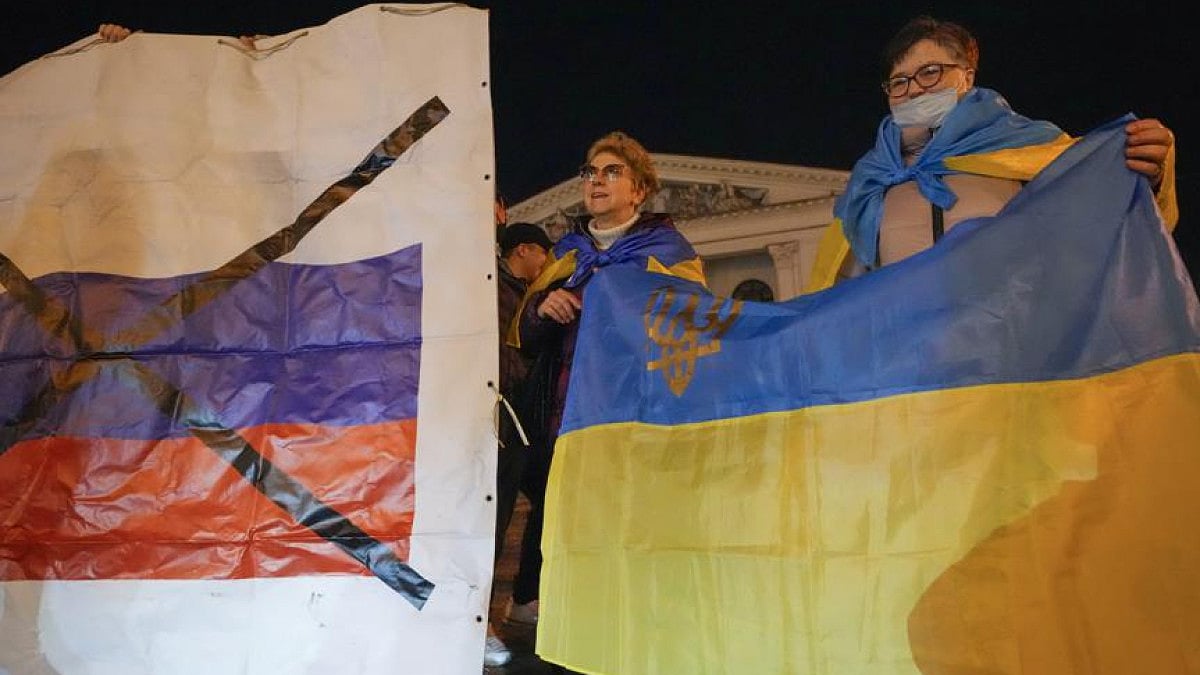 Ukrainians hold up their country's flag (right) as they attend a patriotic protest