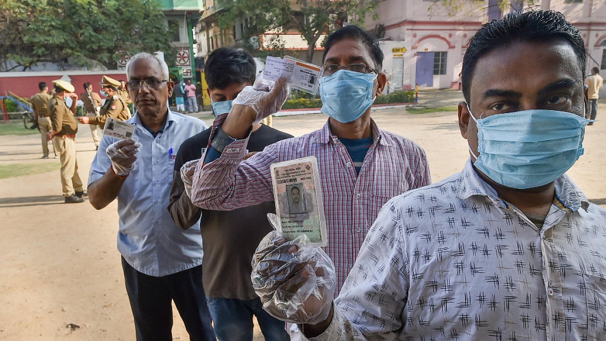 Citizens show their identification cards as they wait to cast their vote, during the 7th phase
