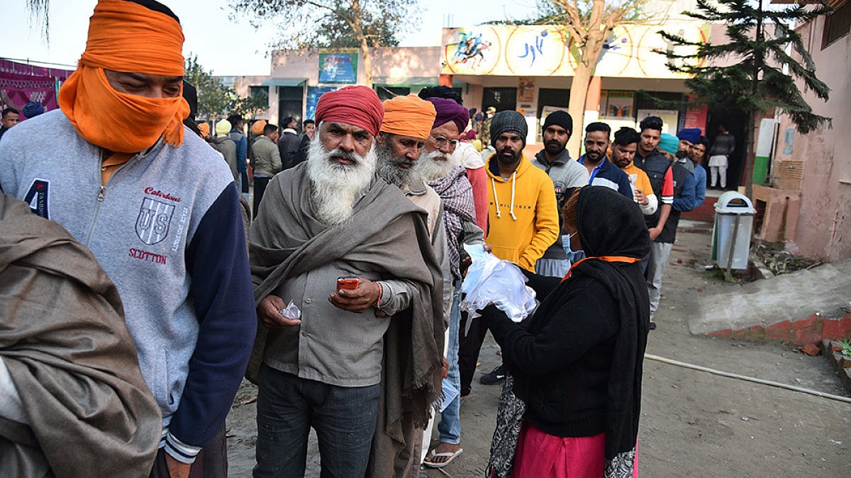People stand in a queue to cast their vote at polling station near the India-Pakistan border for the