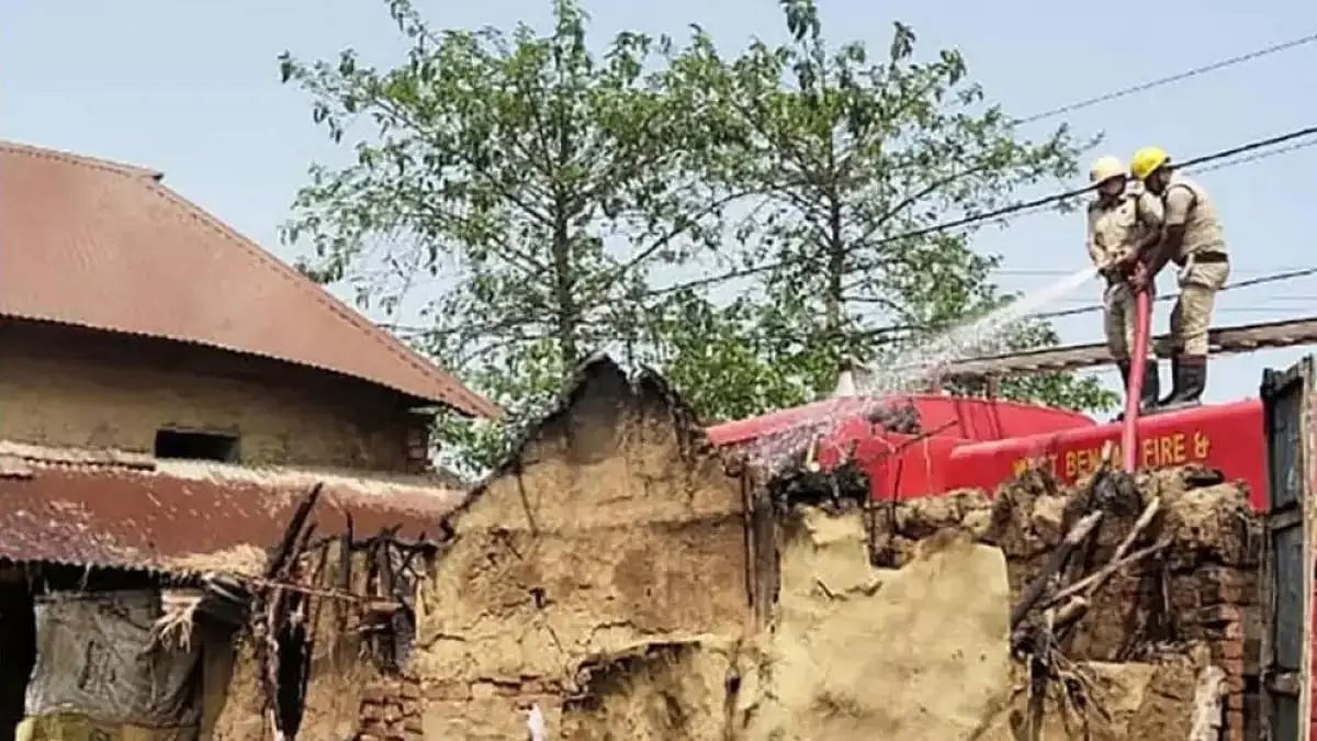 Fire service personnel pouring water in a house that was burnt