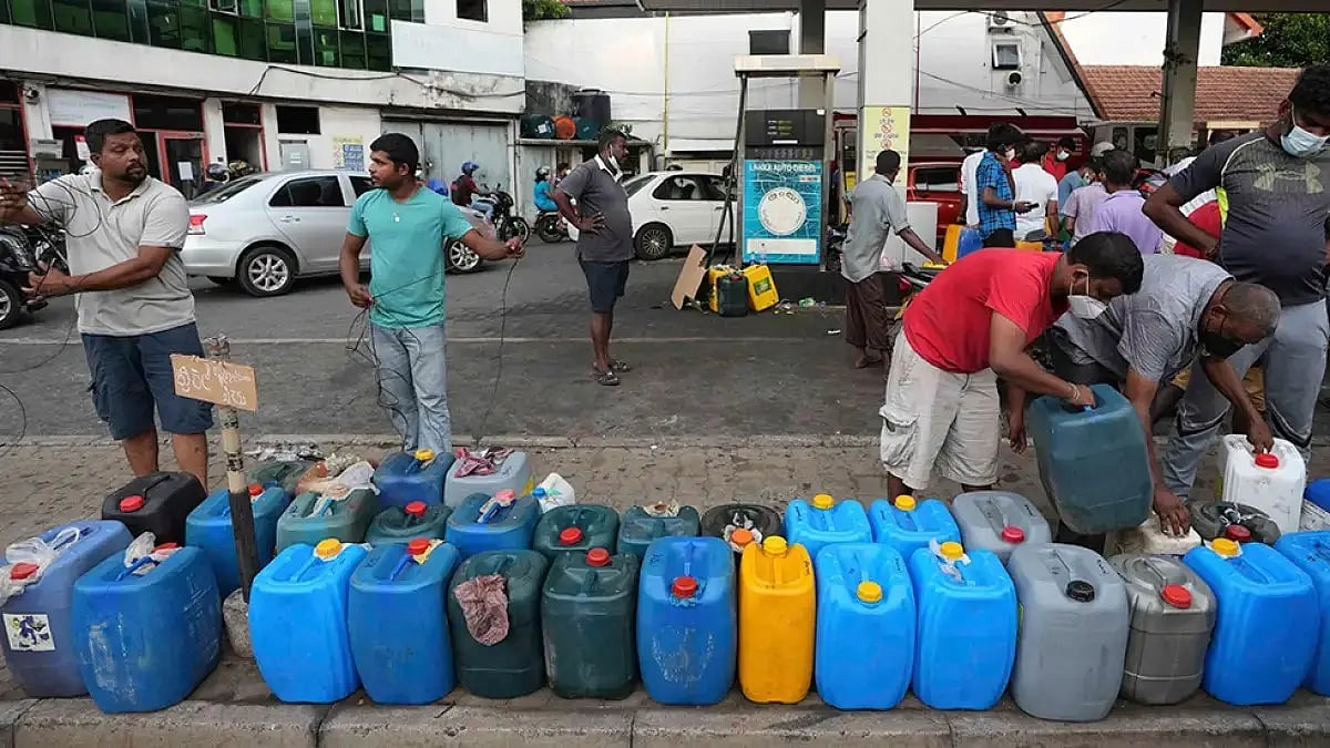 People line up with containers at a fuel pump