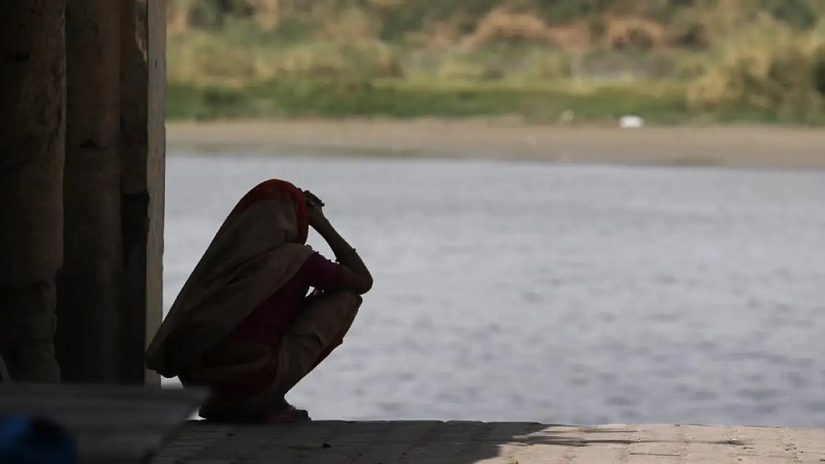 A woman sits in the shade on the banks of the river Yamuna in New Delhi.