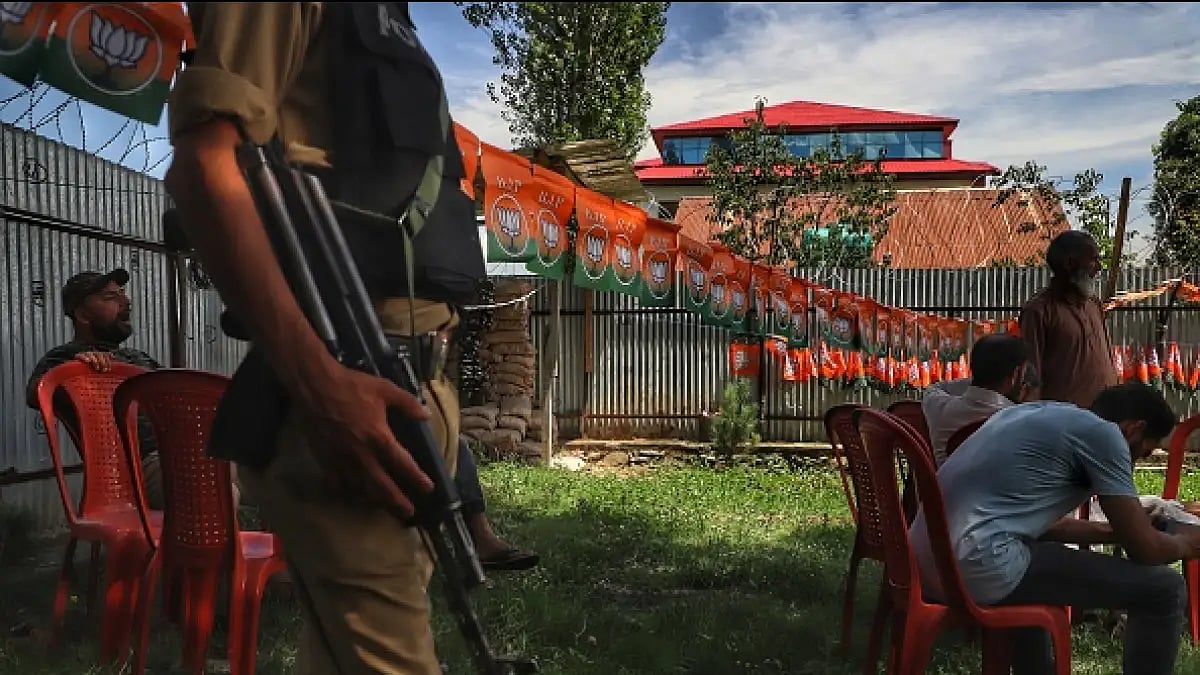 A soldier stands alert while BJP workers take part in a meeting in J-K.